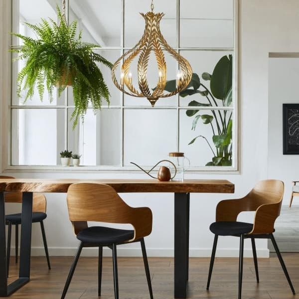 candle style chandelier with gold finish hanging from wooden beams